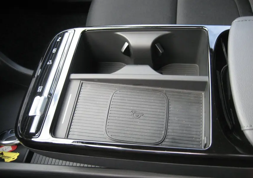 Gros plan sur la console centrale noire du Hyundai Tucson 2025 avec plateau de recharge sans fil et porte-gobelets.