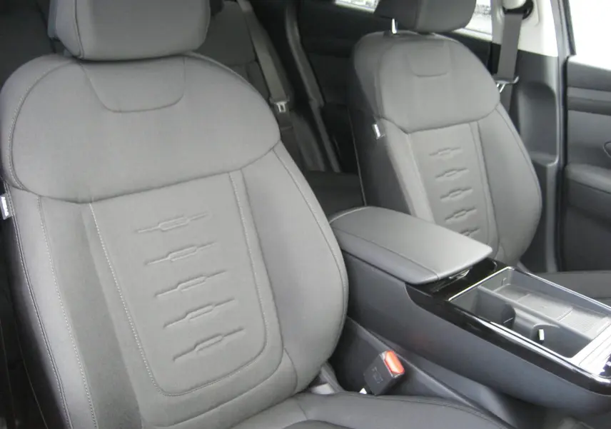 Gros plan sur les sièges avant gris du Hyundai Tucson 2025, finition Style, avec accoudoir central et console épurée.