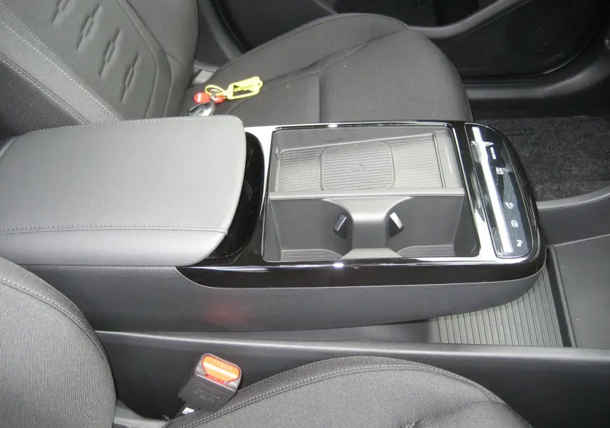 Vue rapprochée de la console centrale noire et grise du Hyundai Tucson 2025, avec porte-gobelets et accoudoir en tissu.