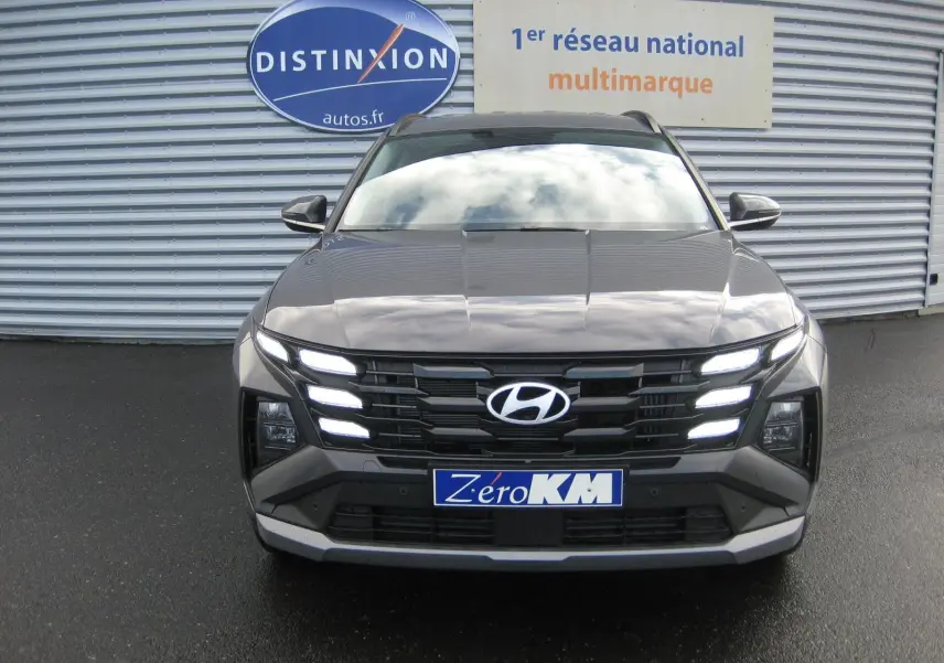 Vue frontale d'un Hyundai Tucson 2025 gris Ecotronic avec feux LED allumés sur un parking extérieur.