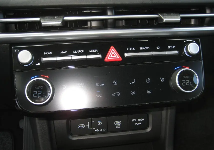 Tableau de bord du Hyundai Tucson 2025 en gris, montrant la console centrale avec commandes climatisation et multimédia.