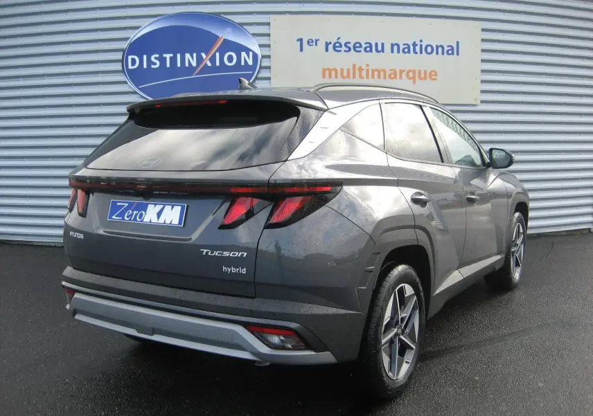 Vue 3/4 arrière droite du Hyundai Tucson 2025 hybride en gris Ecotronic, avec feux arrière LED et jantes alliage distinctives.
