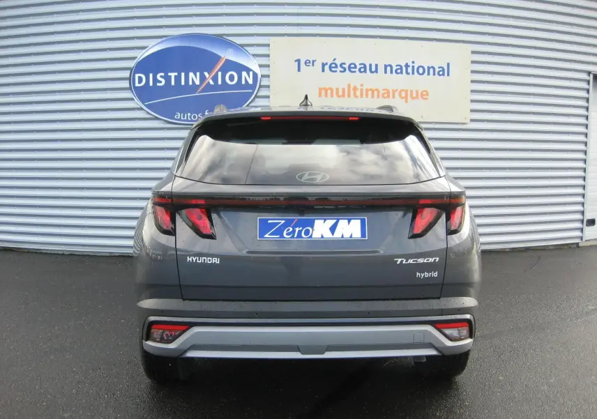 Vue arrière d'un Hyundai Tucson hybride 2025 en gris Ecotronic, avec feux arrière LED et logo "hybrid" visible.