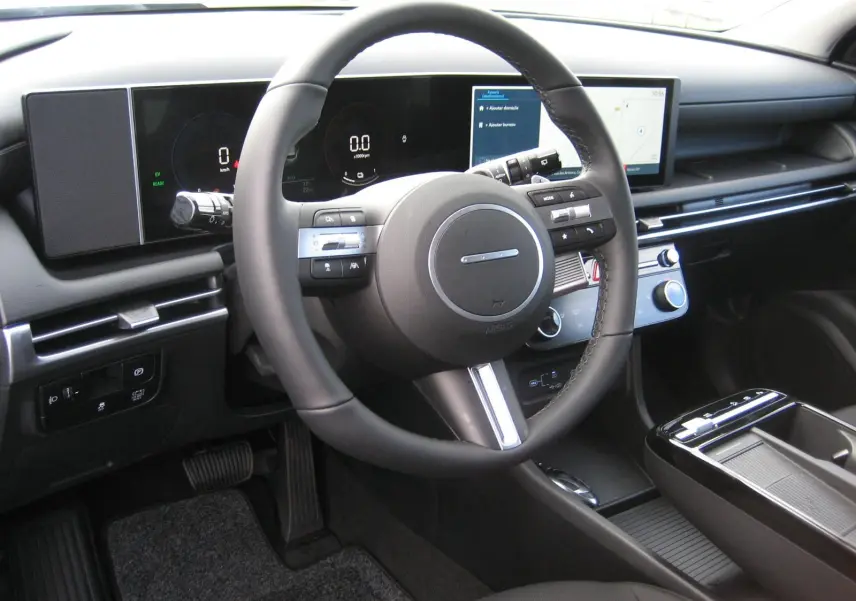 Vue intérieure du tableau de bord et volant du Hyundai Tucson 2025, avec écran digital large et commandes intégrées au volant.