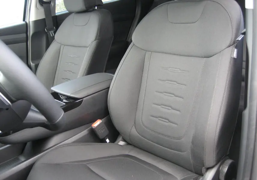 Gros plan sur les sièges avant gris foncé du Hyundai Tucson 2025, avec accoudoir central et ceinture de sécurité visible.