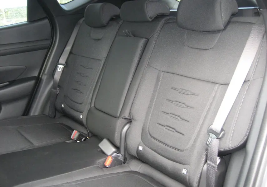 Vue intérieure des sièges arrière noirs du Hyundai Tucson IV PH.2 Style 1.6 T-GDI Hybrid 215, avec appuie-têtes et ceintures visibles.