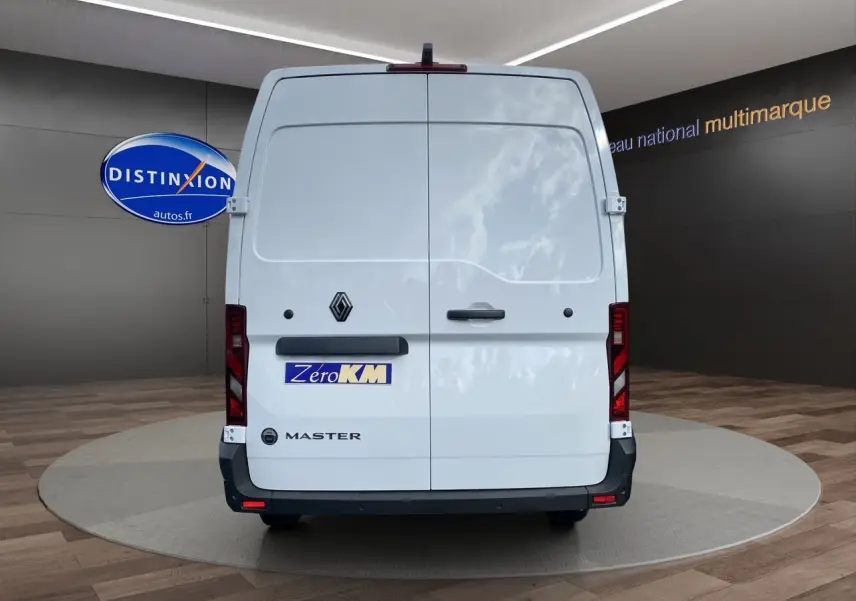 Vue arrière d’un Renault Master blanc 2025 avec portes battantes et logo distinctif sur fond de showroom.