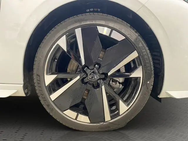 Gros plan sur la roue avant gauche de la Peugeot 308 blanche Okenite, mettant en valeur la jante noire et argentée au design moderne.