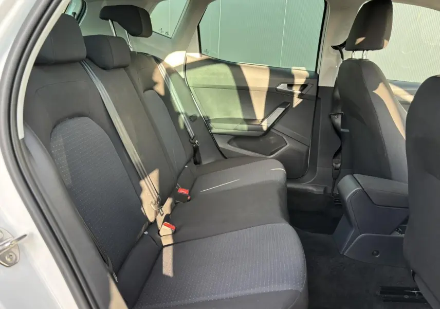 Vue intérieure côté gauche des sièges arrière noirs du SEAT Arona blanc, mettant en valeur l'espace et les ceintures de sécurité.