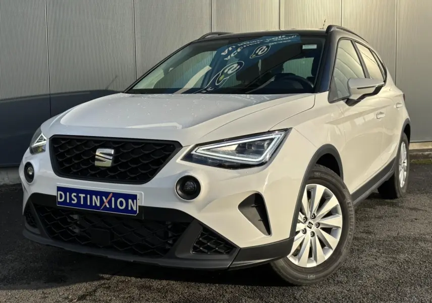 SEAT Arona blanc en 3/4 avant droit, avec calandre noire et jantes alliage 16 pouces visibles.