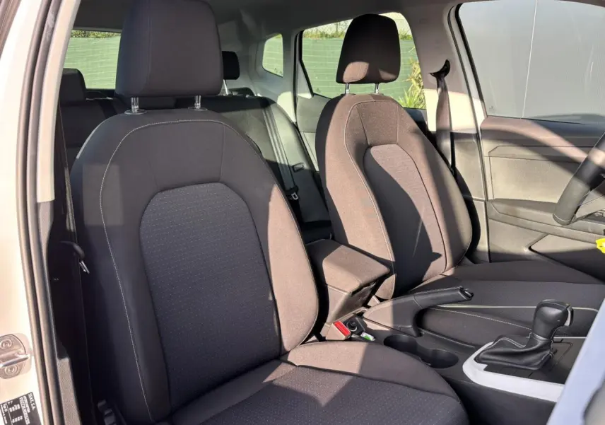 Vue intérieure côté droit montrant les sièges avant en tissu gris et la console centrale avec levier de boîte automatique.