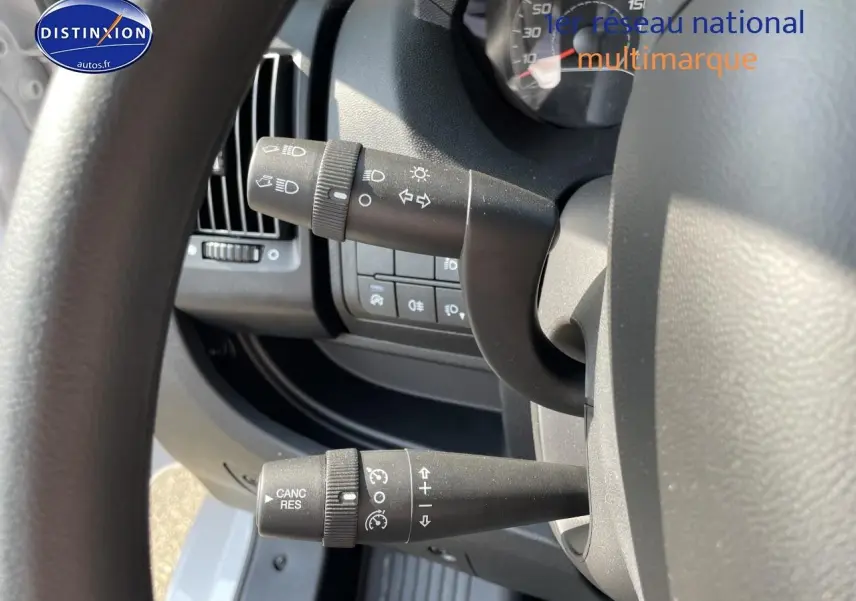Gros plan sur les commandes au volant du Peugeot Boxer Fourgon blanc, côté gauche du poste de conduite.