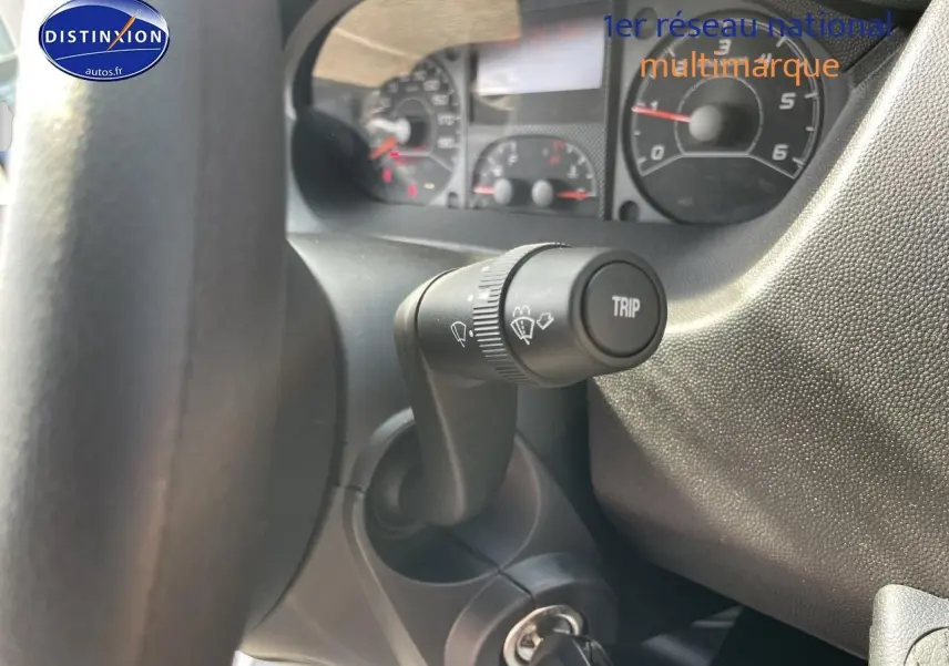 Gros plan sur la manette de commande d’essuie-glace et le tableau de bord du Peugeot Boxer Fourgon blanc, intérieur noir.