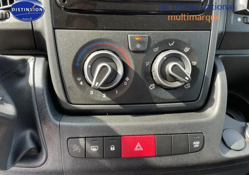 Gros plan sur la console centrale du Peugeot Boxer Fourgon 2023, montrant les commandes de climatisation et les boutons de sécurité.