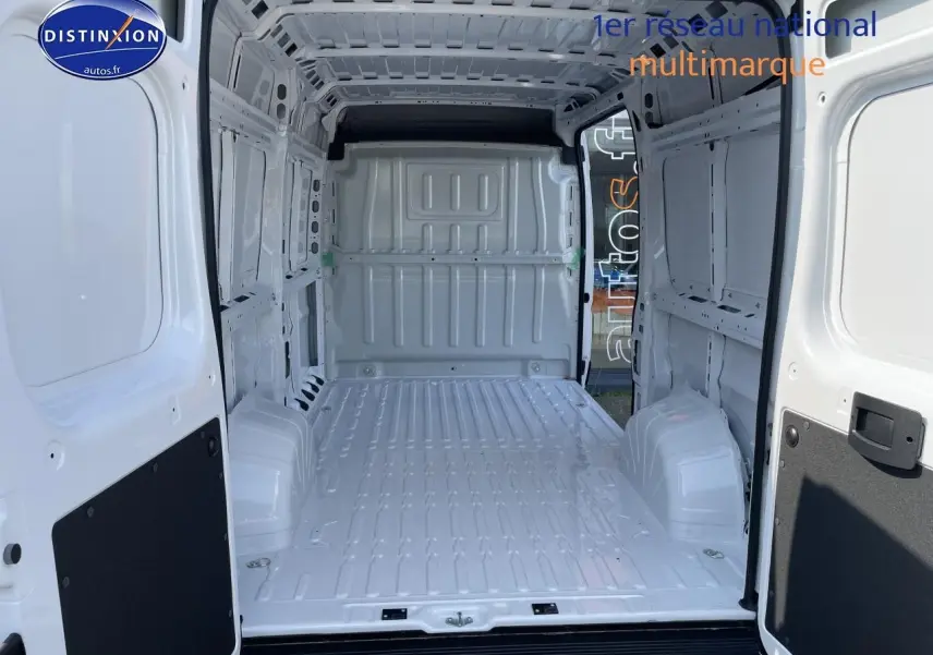 Intérieur du fourgon Peugeot Boxer blanc vu de l’arrière, montrant l’espace de chargement vide et la porte ouverte.