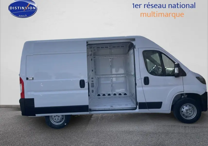 Vue latérale gauche d’un Peugeot Boxer blanc 2023 avec porte coulissante ouverte dévoilant l’espace de chargement vide.
