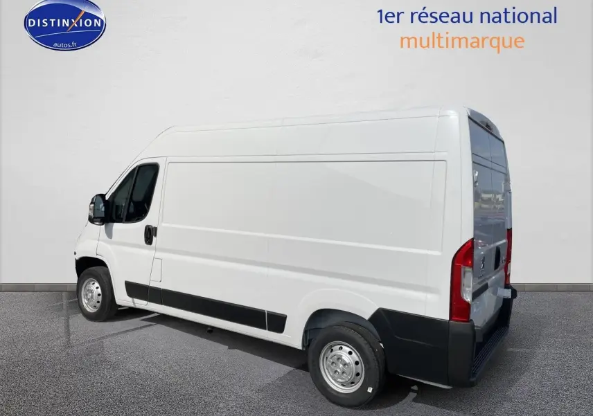 Vue 3/4 arrière droite d’un Peugeot Boxer Fourgon blanc, avec protections noires sur les bas de caisse et pare-chocs.