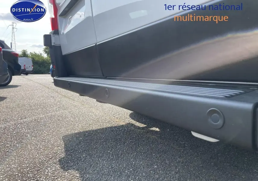 Vue en gros plan du bas côté droit du Peugeot Boxer Fourgon blanc, mettant en valeur la protection latérale noire.