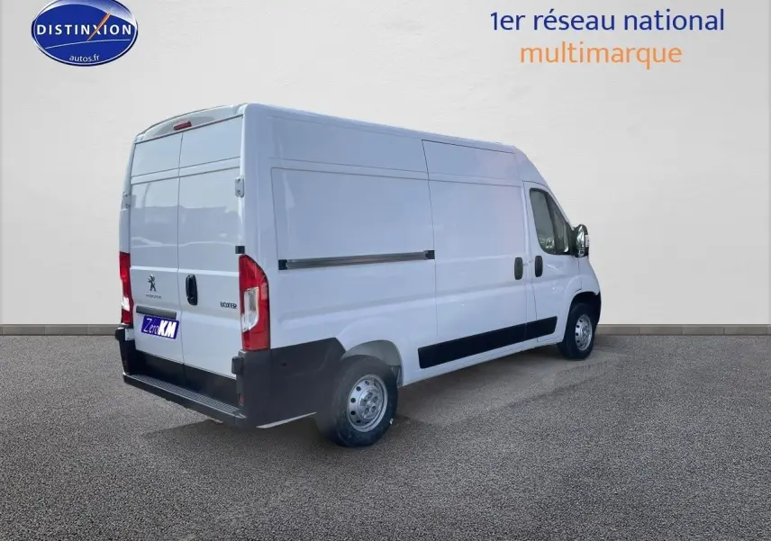 Vue 3/4 arrière droite d’un Peugeot Boxer Fourgon blanc 2023 avec porte latérale et hayon arrière fermé.