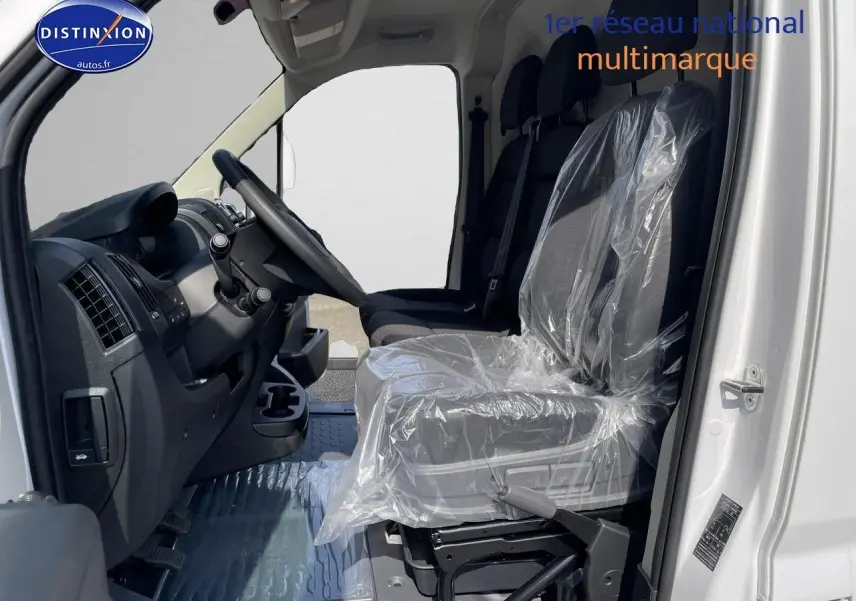 Intérieur côté conducteur du Peugeot Boxer Fourgon blanc 2023, sièges avant protégés par film plastique.