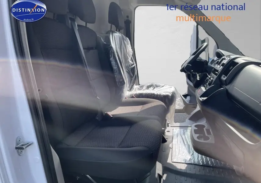 Vue intérieure côté gauche du Peugeot Boxer Fourgon blanc 2023, montrant les sièges avant en tissu noir et le tableau de bord.