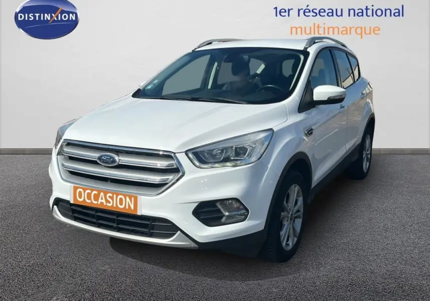 Ford Kuga blanc en 3/4 avant droit avec barres de toit et jantes alliage visibles sur sol gris.