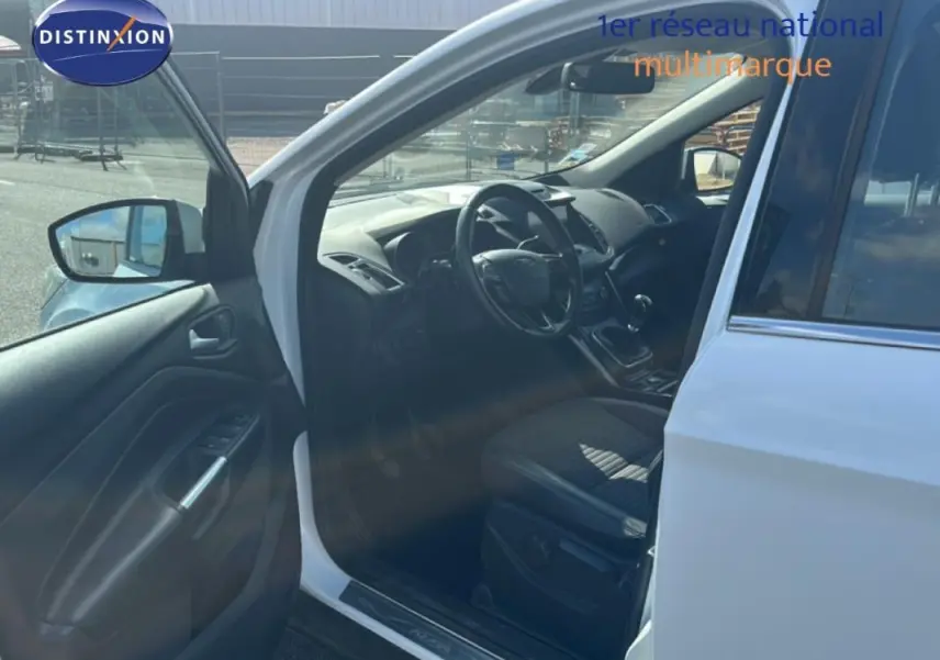 Vue côté conducteur d’un Ford Kuga blanc 2019 avec porte ouverte, montrant l’intérieur et le volant cuir.