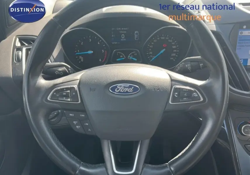 Vue rapprochée du volant cuir noir du Ford Kuga 2019 avec commandes intégrées et tableau de bord digital.