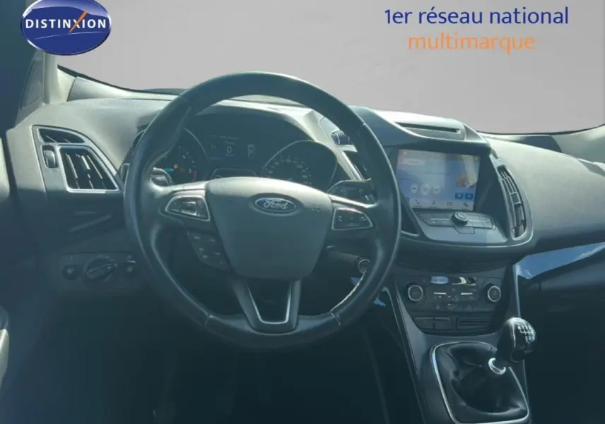 Vue intérieure du tableau de bord et volant cuir noir d’un Ford Kuga 2019 avec écran tactile et boîte manuelle.