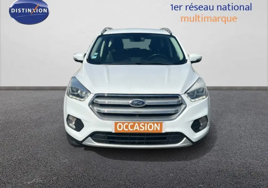 Vue frontale d'un Ford Kuga blanc 2019 avec calandre chromée et phares halogènes allumés.