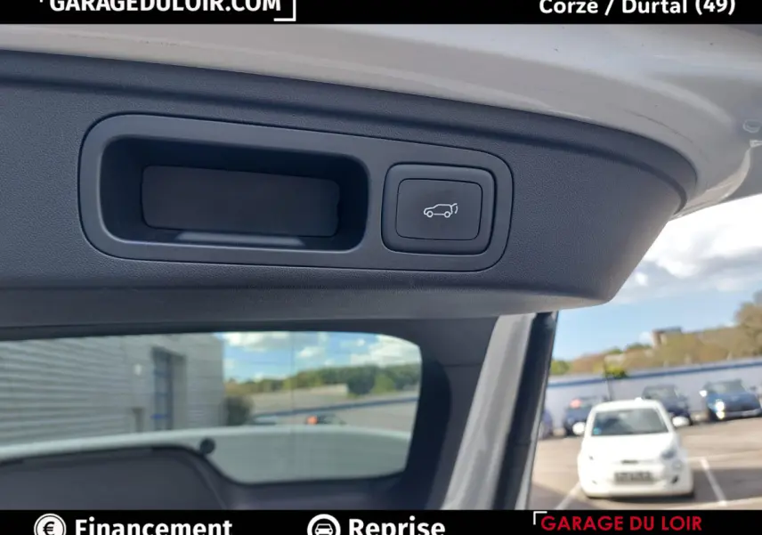 Détail intérieur du hayon ouvert du MG MOTOR EHS 2025, bouton de fermeture électrique visible sur fond clair.