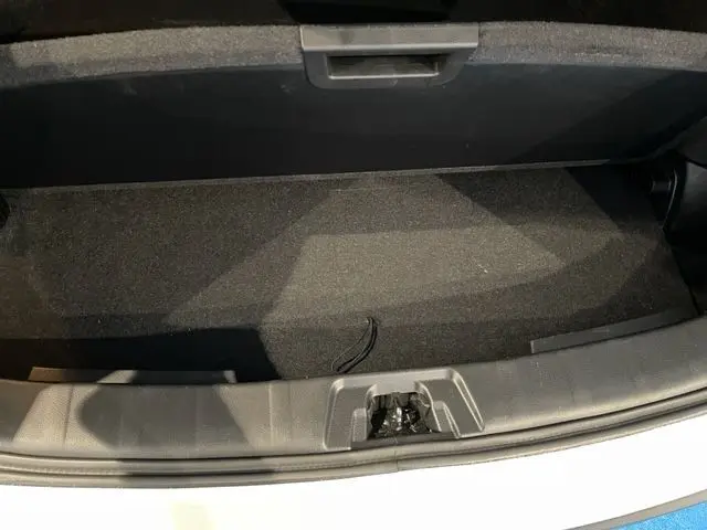 Coffre ouvert du Nissan Qashqai blanc lunaire métal, vue plongeante sur l'espace de rangement vide.