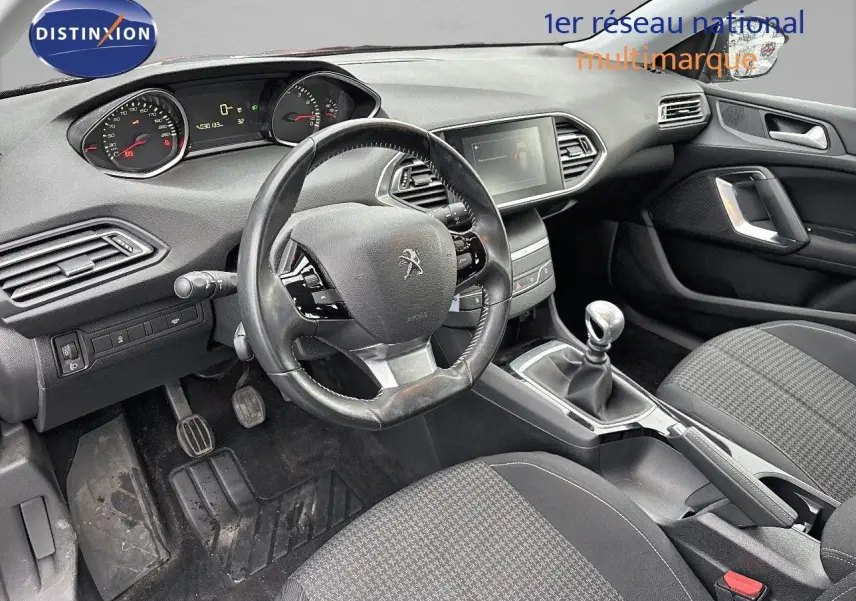 Intérieur de la Peugeot 308 gris Artense, vue côté conducteur, volant compact et levier de vitesse manuel visible.