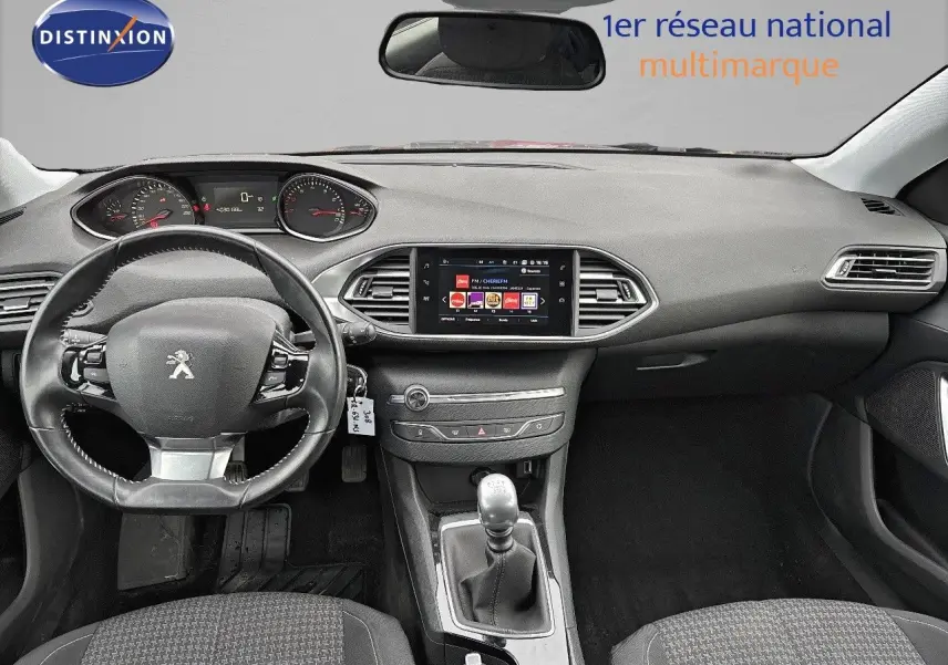 Intérieur de la Peugeot 308 gris Artense, vue frontale du tableau de bord avec volant et écran tactile central.