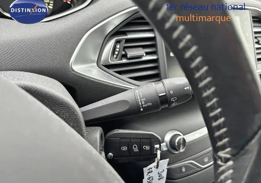 Gros plan sur la commande d’essuie-glace et la clé insérée dans le contact d’une Peugeot 308 gris Artense de 2019.