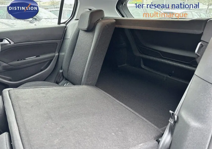 Vue intérieure arrière droite de la Peugeot 308 gris Artense avec siège rabattable et espace de coffre visible.