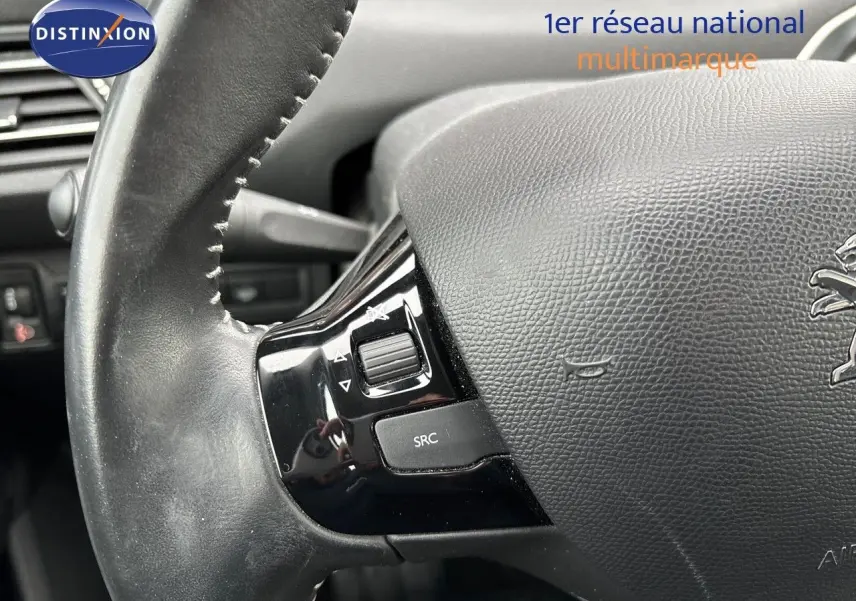 Gros plan sur le volant en cuir noir avec commandes intégrées d'une Peugeot 308 gris Artense de 2019.