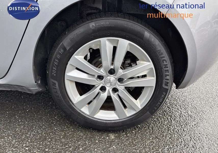 Gros plan sur la roue avant droite d'une Peugeot 308 gris Artense avec jante alliage 16 pouces et pneu Michelin.