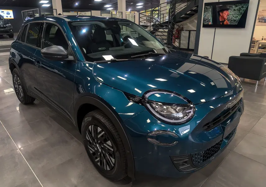 Vue 3/4 avant gauche d'un FIAT 600 Hybrid bleu Sea en showroom, avec phares ronds et jantes noires stylisées.