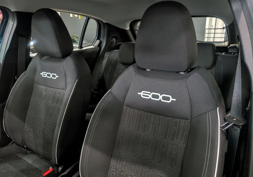Gros plan sur les sièges avant noirs avec logo 600 blanc et motifs FIAT en relief dans l'habitacle d'une FIAT 600 bleu Sea.