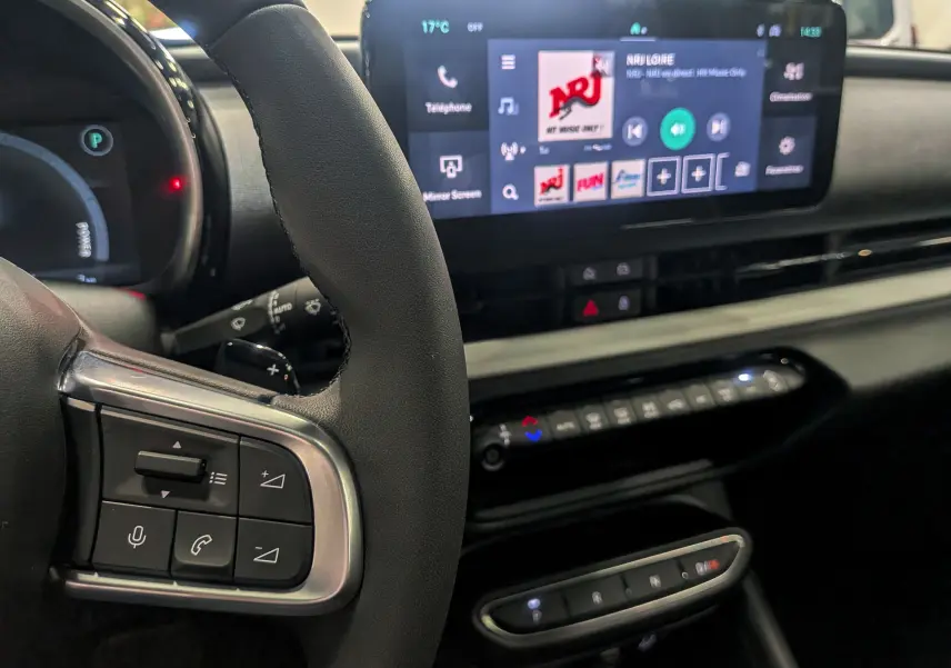 Vue rapprochée du volant et tableau de bord numérique de la FIAT 600 Hybrid 2025 avec écran tactile affichant NRJ.