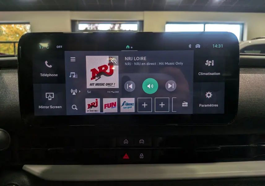 Écran tactile central du tableau de bord de la FIAT 600 Hybrid 2025 affichant la radio NRJ en intérieur voiture.