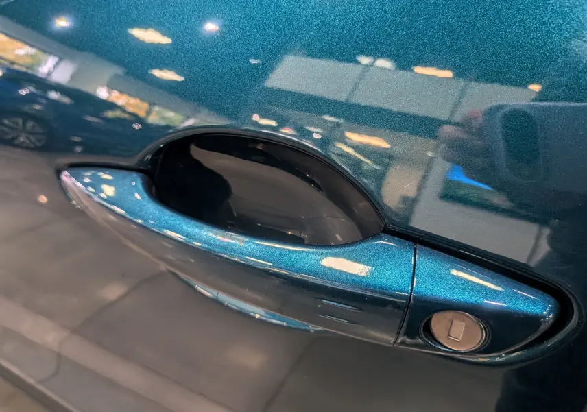 Poignée de porte côté gauche bleu Sea métallisé de la FIAT 600 Hybrid 2025 avec serrure intégrée visible.