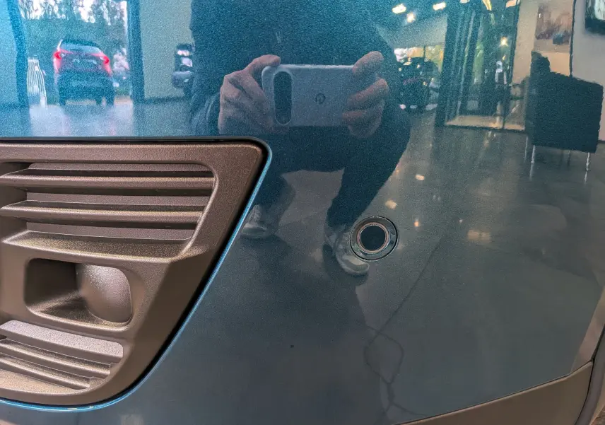 Détail du pare-chocs avant bleu Sea de la FIAT 600 Hybrid 2025 avec capteur de stationnement rond visible.