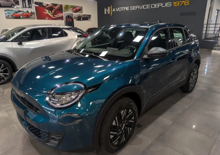 Fiat 600 1.2 Hybrid bleu Sea vue 3/4 avant droit en intérieur, avec jantes noires et détails chromés.