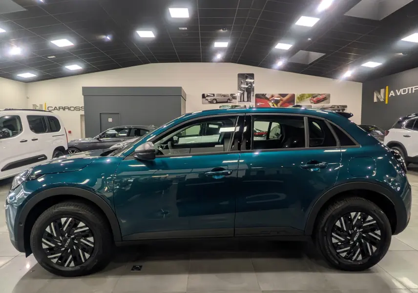 Vue de profil côté gauche d'une FIAT 600 1.2 Hybrid bleu Sea en showroom, soulignant ses jantes noires et son design compact.