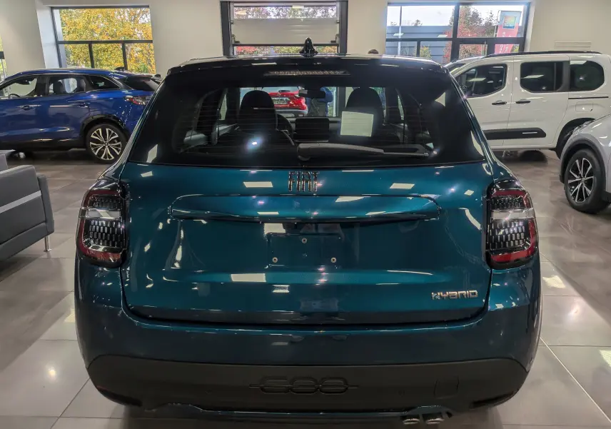 Vue arrière d'une FIAT 600 1.2 Hybrid bleu Sea en showroom, avec feux arrière au design moderne et logo Hybrid visible.