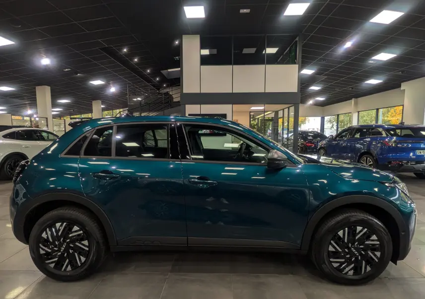 Vue de profil côté gauche d'une FIAT 600 1.2 Hybrid 145 CH eDCT6 POP en bleu Sea dans un showroom lumineux.