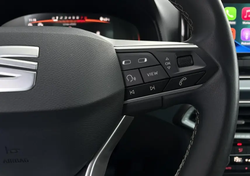Gros plan sur le volant noir du SEAT Arona 2025 avec commandes multifonctions et combiné digital en arrière-plan.