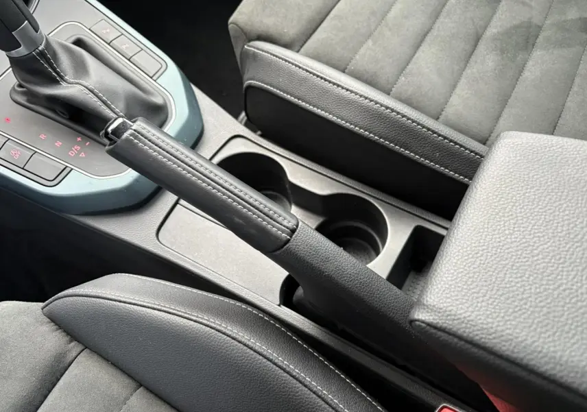 Gros plan intérieur sur la console centrale et frein à main du SEAT Arona TSI 115 DSG Xpérience, sièges gris.